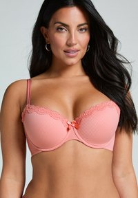 Pfirsichfarbener gepolsterter BH mit gerippter Textur, floraler Spitzenkante und einer kleinen Satinschleife in der Mitte. Verstellbare Träger.