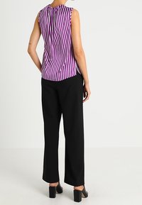Purple and white striped sleeveless top with gathered neckline, paired with black wide-leg trousers and block-heeled shoes.