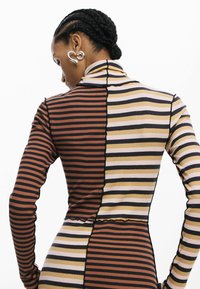 Langärmliges Kleid mit vertikalen Streifen in Braun, Beige und Schwarz. Verfügt über einen hohen Kragen und ein strukturiertes, geripptes Gewebe mit kontrastierenden Abschnitten.