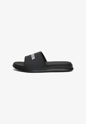 Black slide sandals featuring a wide strap with white branding, a textured insole, and a cushioned sole for comfort.