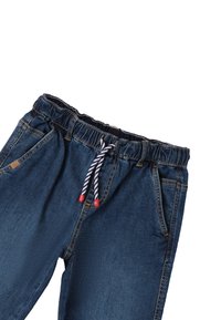 Joggers de mezclilla con cintura elástica, cordón oculto y detalles en rojo. Con bolsillos laterales y un lavado medio.