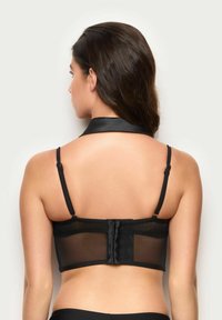 Sort mesh-bh med en glat satinkrave, justerbare stropper og lukning med hægte og øje på ryggen. Gennemsigtigt materiale tilføjer tekstur.