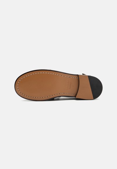 Suela de zapato de cuero con un color marrón claro, forma redondeada, costura distintiva y un tapón de caucho negro en el talón. Textura suave en general.