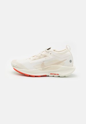 Witte hardloopschoen met een gestructureerde bovenkant, van synthetisch materiaal, ronde neus en een oranje loopzool. Bevat een logo en minimalistische ontwerpelementen.