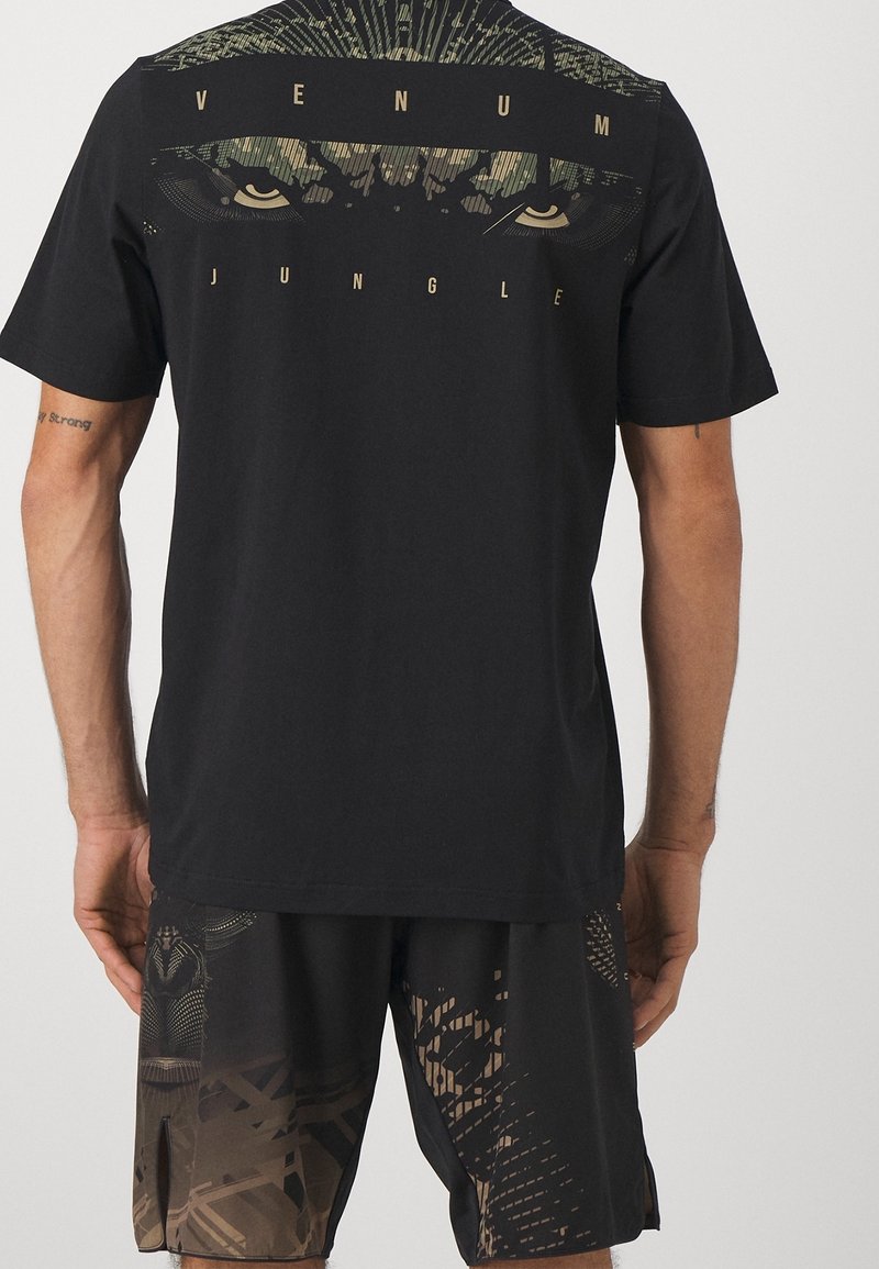 Camiseta negra con un diseño de ojo de animal estilizado y las palabras "VENUM JUNGLE" en la parte de atrás, combinada con pantalones cortos negros con estampado.