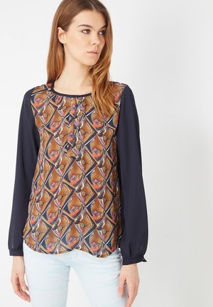 Blusa de manga larga con un frente de patrón floral marrón y mangas azul marino, con un cuello redondo y detalles de botones. Textura suave.