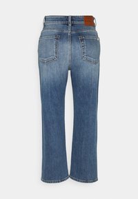 Jean en denim bleu vu de dos avec deux poches plaquées, une étiquette en cuir de la marque sur la ceinture, et une coupe droite.