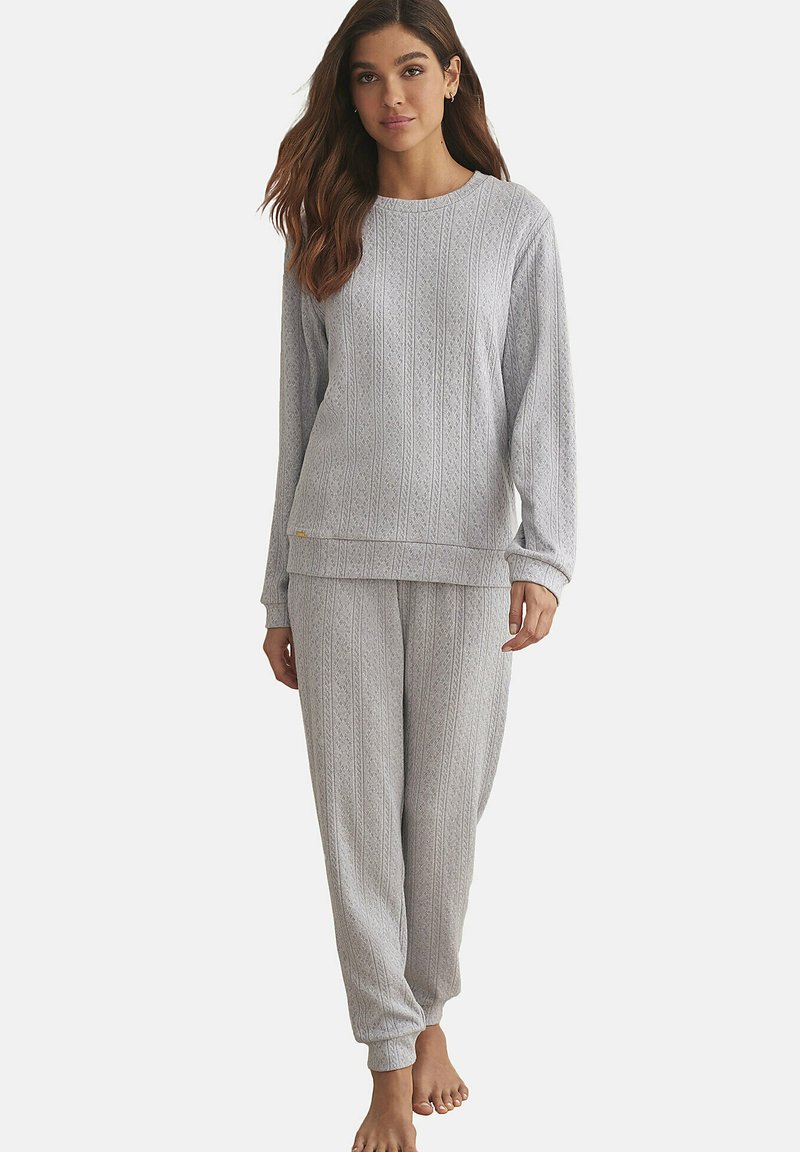 Grijs loungewear set met een gestructureerde, gemusterde lange mouw top en bijpassende broek, beide met geribbelde manchetten en een ontspannen pasvorm.