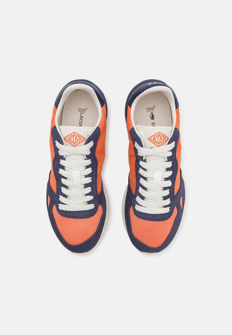 Zapatillas con malla naranja y detalles en ante azul marino, con cordones blancos y un logotipo en la lengüeta. Suela de goma circular.