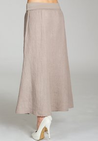 Hellbrauner Leinen-Maxi-Rock mit breitem Bund, fließendem Design und Saum knapp über dem Knöchel, kombiniert mit weißen High Heels.