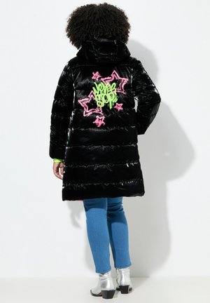 Manteau matelassé noir brillant avec un design graphique vert et rose de étoiles et de texte au dos. Il possède une capuche et des coutures épaisses.