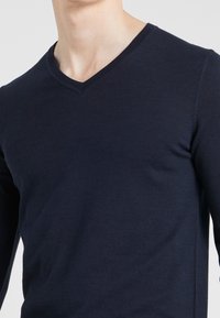 Marinblå långärmad V-ringad tröja i mjukt tyg, med en enkel design och figursydd passform samt texturerad krage.