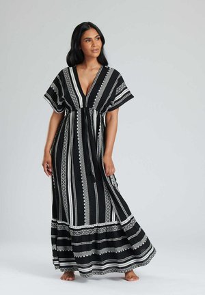Robe maxi à rayures noires et blanches, dotée d'un décolleté en V profond, de manches courtes et d'une taille à nouer. Le tissu présente un motif texturé et un design fluide.