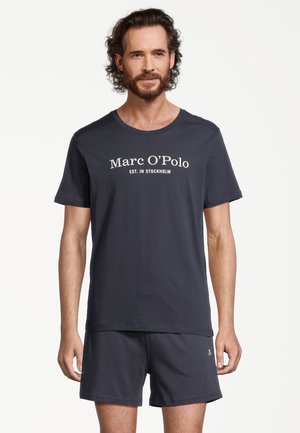 Dunkelblaue Baumwoll-T-Shirt mit kurzen Ärmeln, mit Rundhalsausschnitt und weißem Text "Marc O'Polo EST. IN STOCKHOLM." Kombiniert mit passenden Shorts.