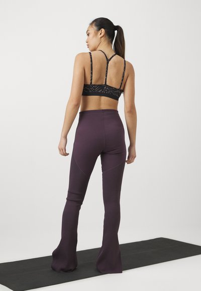 Svart mönstrad sport-bh och lila utsvängda leggings. Bh:n har tunna remmar; leggings har ribbade detaljer och en smooth yta.