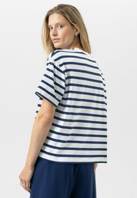 T-shirt à manches courtes rayé en blanc et marine. Coupe décontractée, texture douce, avec un col rond. Porté ici avec un pantalon marine.