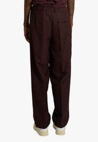 Pantaloni bordeaux a gamba larga con una texture liscia, dotati di tasca posteriore e vita elastica per il massimo comfort.
