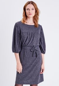 Vestido de punto gris con escote redondo, mangas abullonadas, cinturón en la cintura y cuerpo fruncido. Textura suave, diseño de longitud media.