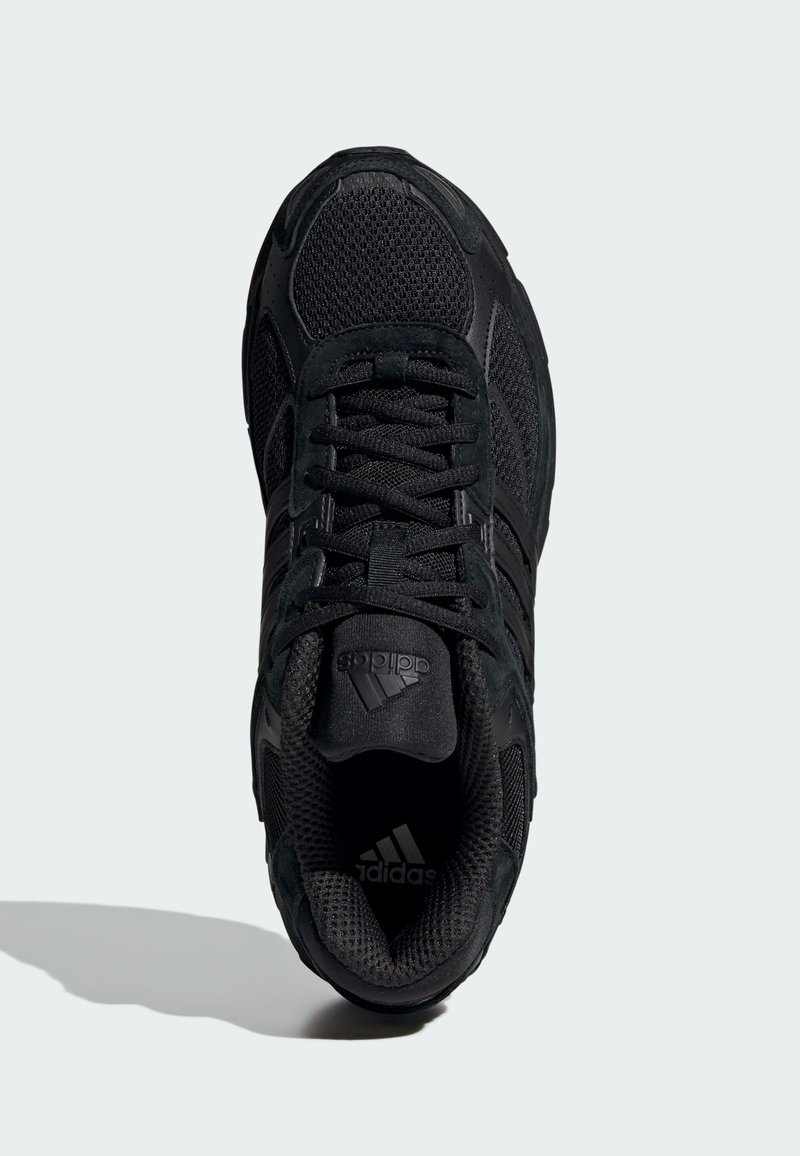 Scarpa sportiva nera con tomaia in rete, dettagli testurizzati e lacci piatti. La suola presenta un motivo distintivo per la trazione.