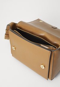 Sac en cuir marron au design structuré, doté d'un intérieur zippé, d'une fermeture à rabat magnétique et d'accents en métal doré.