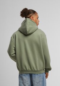 Hooded sweatshirt in muted green, cotton blend. Features a relaxed fit, ribbed cuffs and hem, with a clean back design. Casual overall look.