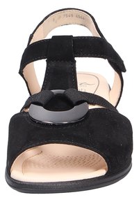 Sandalo in suede nero con punta aperta, caratterizzato da una fascia larga e un accento in hardware nero circolare. Soletta imbottita color beige con texture perforata.