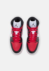 Paire de baskets Air Jordan rouges, noires et blanches avec des lacets rouges vues de dessus sur fond blanc.