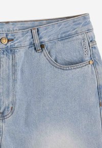 Jasnoniebieskie dżinsy z efektem gradientu, miedziane nity i kontrastowe szwy. Wyhaftowane logo na przedniej kieszeni.