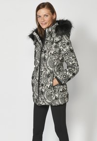 Melnbalts paisley raksts pufīgais mētelis ar mākslīgo kažokādu kapuci, ar rāvējslēdzēju priekšpusē, divām sānu kabatām un elastīgiem aprocēm.