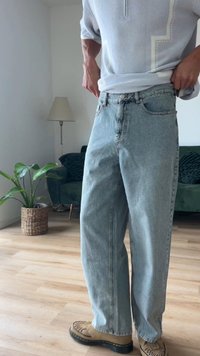 Ανοιχτό μπλε, φαρδιά τζιν παντελόνια με ψηλή μέση και σχέδιο πέντε τσεπών, συνδυασμένα με μπεζ υποδήματα.