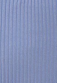 Gros plan sur un tissu tricoté bleu clair avec une texture côtelée verticale et des motifs de fil entrelacés visibles.