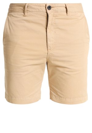 Beige cotton shorts with a zip fly and button closure, featuring side pockets and a smooth texture. Hemmed at mid-thigh length.