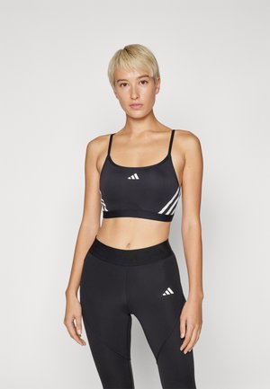Svart trenings-BH med hvite diagonale striper og logo. Glatt stoff, tynne stropper, og matchende høytlivede svarte tights med logo.