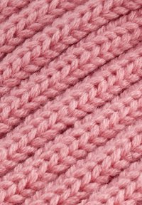 Strickstoff aus weichem rosa Garn, mit einem strukturierten, geflochtenen Muster und sichtbaren Fäden, das ein flauschiges, gemütliches Aussehen hat.