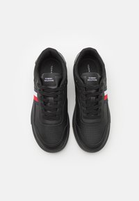 Czarne sneakersy wykonane z materiału syntetycznego, z perforowanymi detalami, płaskimi sznurowadłami oraz trójkolorowym paskiem (czerwonym, białym i niebieskim) po boku.