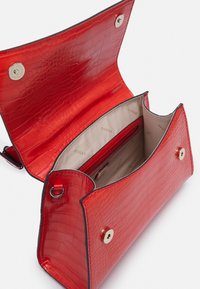 Rote Kunstleder-Handtasche im Krokodil-Look mit glatter Textur, Magnetverschluss und einem beigen Innenraum, der eine Reißverschlusstasche und Branding aufweist.