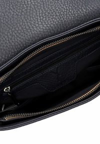 Navy leather bag with pebbled texture, unzipped to reveal a smooth inner lining and zippered pocket, featuring gold-toned zipper hardware.