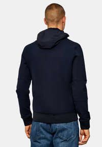 Felpa navy con un ampio cappuccio, maniche lunghe, polsini a coste e una trama uniforme. Presenta una vita aderente e un design casual.