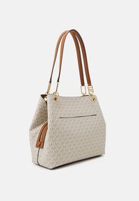 Tote bag van beige stof met een logo-patroon over de hele tas. Bruine leren handvatten, een met rits afsluitbaar zijvak en gouden hardware accenten.
