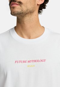 White cotton t-shirt featuring bold text in pink and yellow. Text reads "FUTURE MYTHOLOGY" with additional line in soft yellow below.