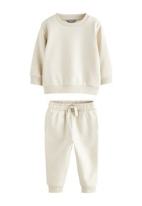 Kermanvärinen collegepaita ja siihen sopivat pehmeästä puuvillasekoitteesta tehdyt jogger-housut. Collegepaidassa on pyöreä pääntie ja resorit hihansuissa; jogger-housuissa on joustava vyötärönauha.