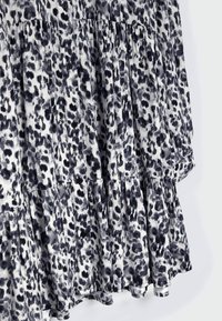 Schwarz-weißes Leopardenmuster-Kleid mit gerafften Stufen, Knopfdetails und einem leichten, strukturierten Stoff.