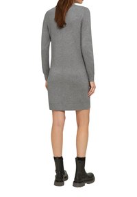 Robe en tricot grise à manches longues, coupe droite et longueur mi-cuisse, assortie à des bottes noires à la cheville avec une semelle épaisse.