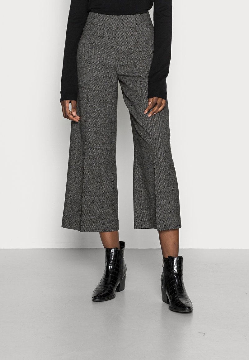 Szare szerokie spodnie z teksturowanej tkaniny, z wysokim stanem i dwiema bocznymi kieszeniami, zestawione z czarnymi ankle bootami w wzór krokodyla.