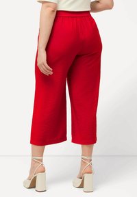 Rode cropped broek met een gestructureerde afwerking, voorzien van een elastische tailleband en een losse pasvorm. Gepaard met off-white plateauhakken.