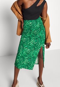 Vihreä marmoroitu midi-hame, jossa on sivuhalkio, pehmeä kangas ja teksturoidulla kuviolla. Yhdistetty mustaan toppiin ja ruskeaan ulkotakkiin.