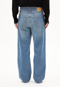 Vaqueros de mezclilla azul de pierna ancha con una cintura alta, cinco bolsillos y un parche de cuero de la marca en la cintura trasera. Acabado limpio sin desgastes.