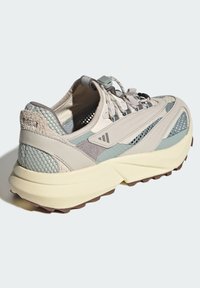 Ľahká bežecká obuv s kombináciou béžových a teal materiálov, so sieťovinovými akcentmi, textúrovaným opätkom a svetlou, polstrovanou podrážkou.