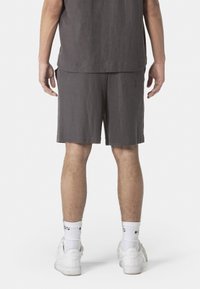 Grau leinene Shorts mit lockerer Passform, ausgestattet mit einer Gesäßtasche, kombiniert mit weißen Sneakers und Socken in Crew-Länge.