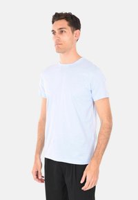 T-shirt azzurro chiaro a maniche corte realizzato in tessuto morbido, con scollatura a girocollo e vestibilità comoda, abbinato a pantaloni neri.